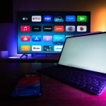 TV inteligente e tablet exibem aplicativos de streaming em uma sala de estar moderna.