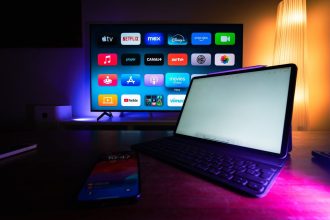 TV inteligente e tablet exibem aplicativos de streaming em uma sala de estar moderna.