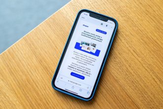 Smartphone exibindo um anúncio de comércio eletrônico sobre uma superfície de madeira.