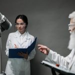 Cientistas em jalecos analisam uma tecnologia robótica em um laboratório, representando pesquisa colaborativa em inteligência artificial.