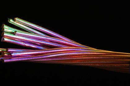 Close de cabos de fibra óptica multicoloridos sobre fundo escuro.