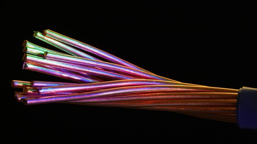 Close de cabos de fibra óptica multicoloridos sobre fundo escuro.
